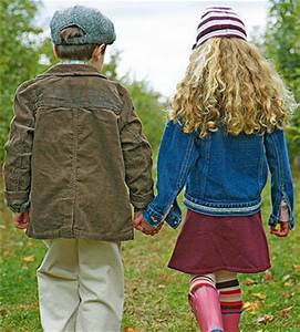 A boy and girl holding hands while walking.