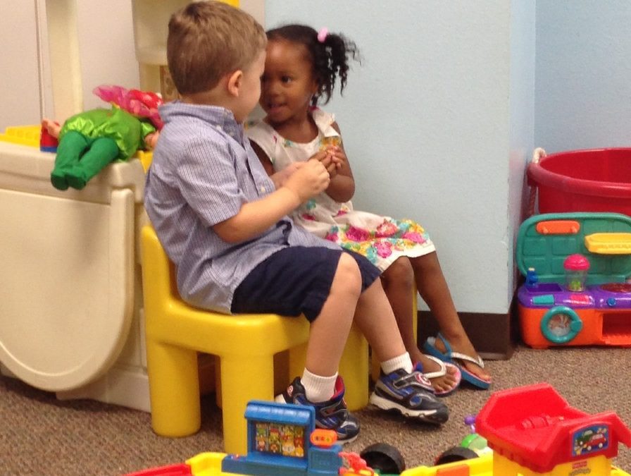 Two children sitting on a yellow chair in the playroom