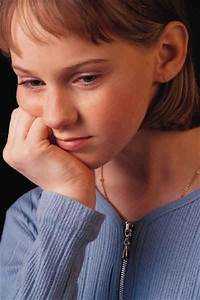 A young girl with her hand on her chin.