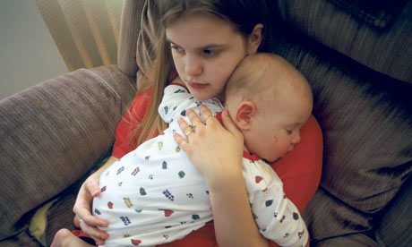 A woman is holding a baby in a chair.