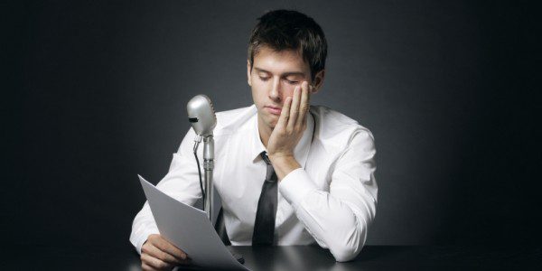 A man sitting at a desk reading a piece of paper.