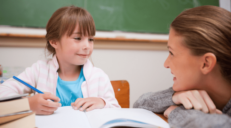 A lady talking with a small girl while teaching in a room