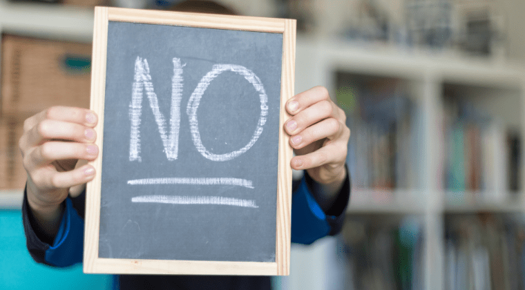 A boy holding a board with no sign on it inside a room